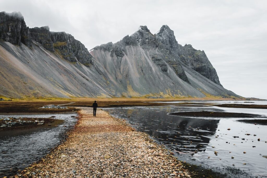 A solitary figure walking toward mountains, suggesting growth and becoming.